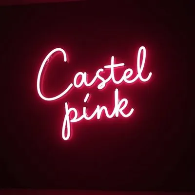 Enseigne au néon rose « Castel Pink » sur un mur sombre